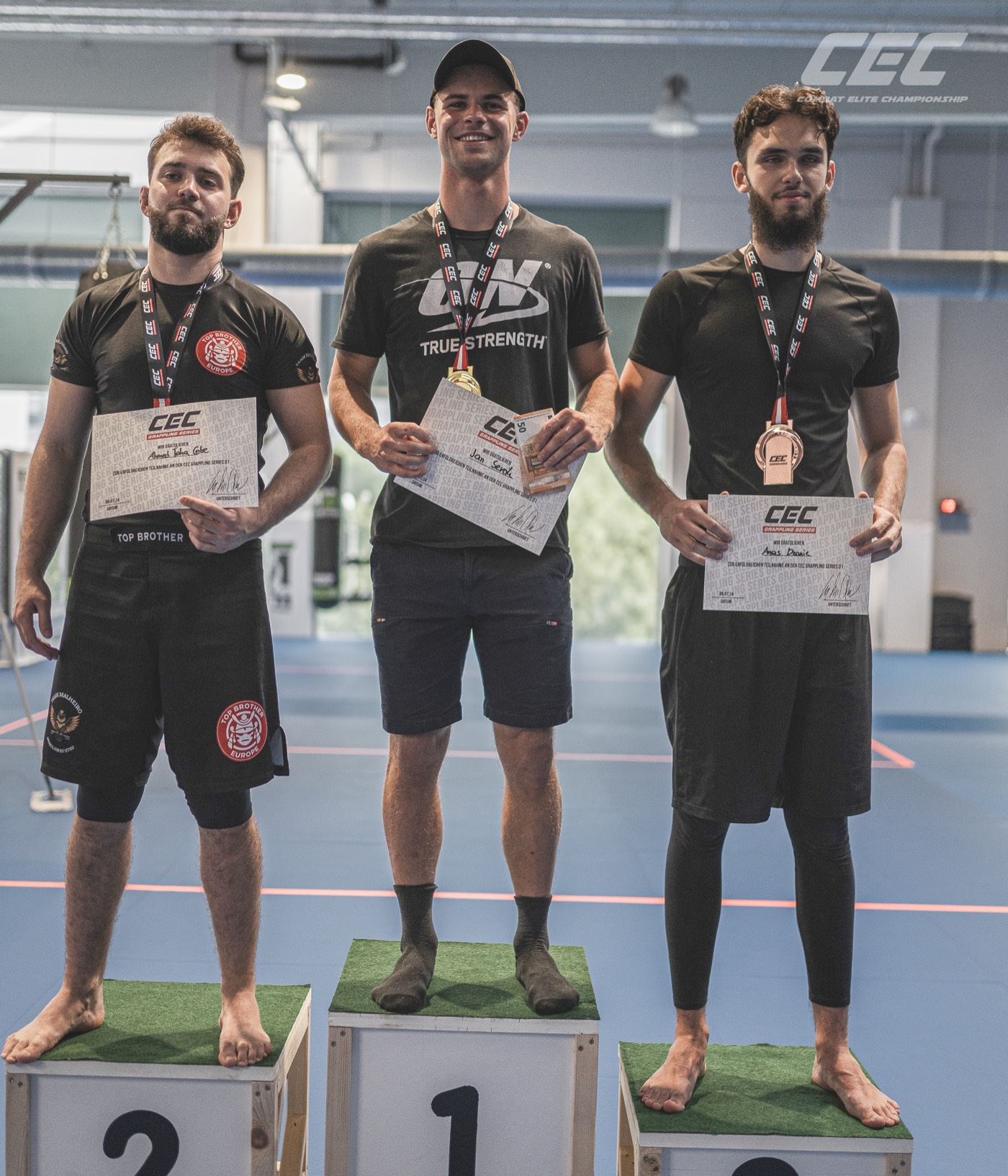 Podium der Erwachsenendivision bei Grappling Series 1 — drei Platzierte mit CEC-Urkunden und Medaillen